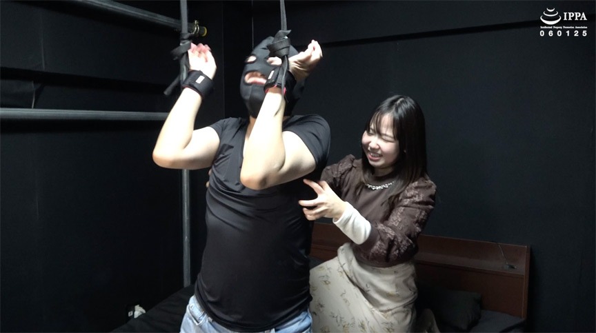 谷田かりながベッドの上にM男を四肢拘束し、下着姿の無防備な状態に対して笑顔で激しく攻め立てるくすぐり調教の全体像。 - Overall studio layout of newcomer Karina Tanida executing an intense tickling routine on a bound submissive asset.